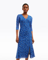 A woman wears the Draper James Selena V-Neck Midi Dress in Blue Scattered Ditsy, featuring three-quarter sleeves and a front slit, standing against a plain white background.