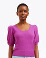 A woman stands against a white background wearing a bright purple Draper James Short Sleeve Cashmere Sweater with puffed sleeves, made from 100% cashmere.