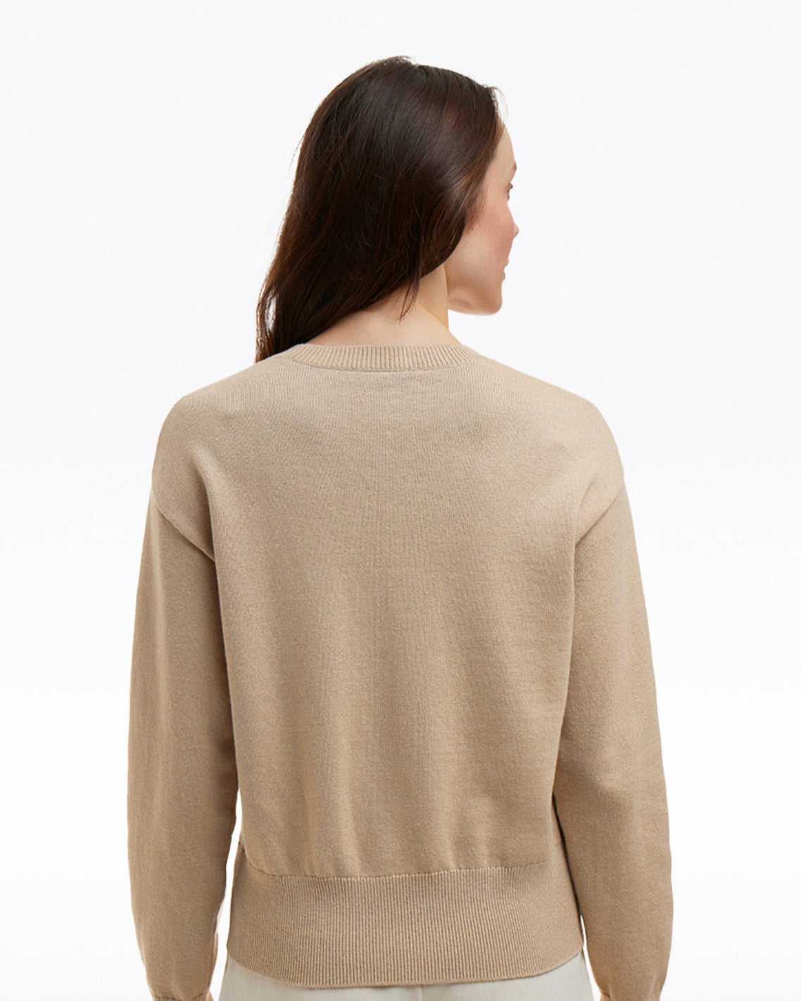 A person with long brown hair is shown from behind, wearing the Draper James Daffodil Crewneck Sweater in a beige cotton-wool blend against a plain white background.