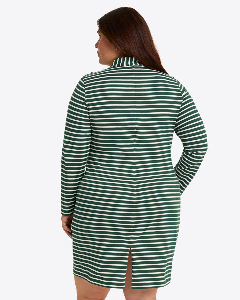 A woman shown from behind wears the Draper James Elsie Turtleneck Dress in Green Stripe, a long-sleeve cotton jersey dress with green and white stripes and a small back slit.