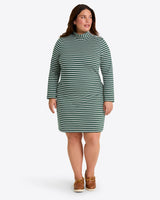 A woman wears the Draper James Elsie Turtleneck Dress in Green Stripe, paired with brown boat shoes, standing against a plain light background.