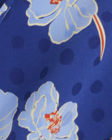 Close-up of the Kellie Babydoll Dress in Printed Dot Jacquard by Draper James, featuring blue and white florals with red accents and dark blue polka dots—ideal for a playful v-neck babydoll style.