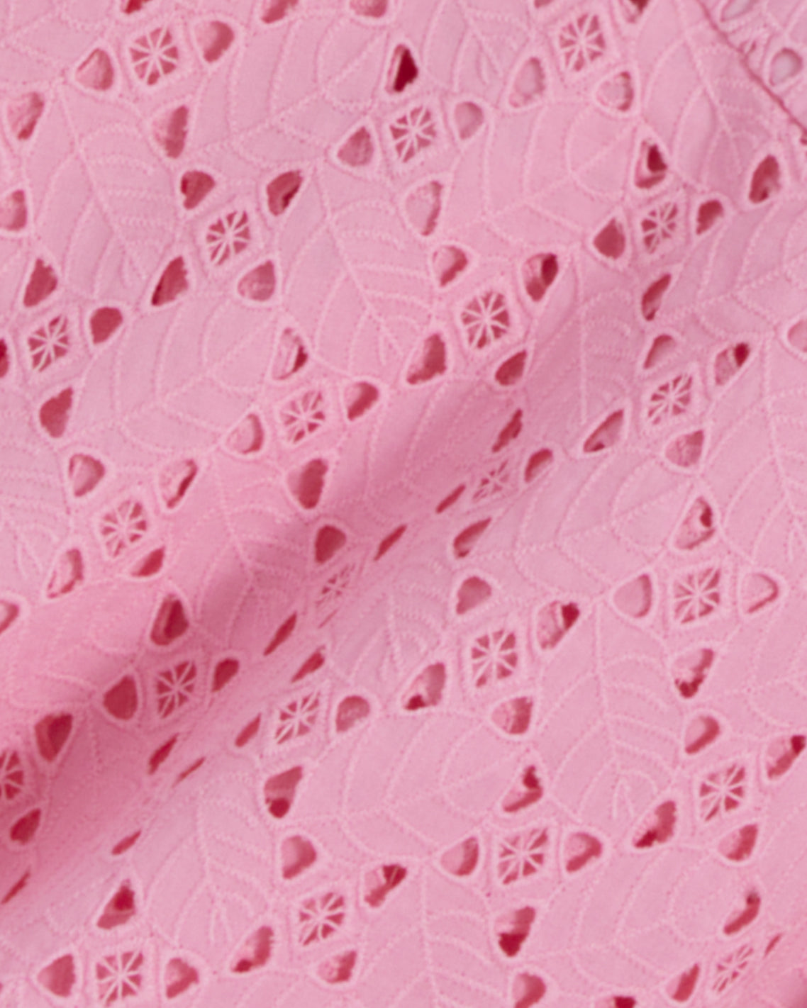 The Caitlyn Midi Dress in Eyelet by Draper James features a close-up of pink lace fabric with a leaf and floral cutout pattern. It has a square neckline and is crafted from delicate cotton eyelet for an elegant touch.