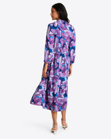 A person in a Draper James Katie Midi Dress with bold floral fabric and white shoes stands facing away.