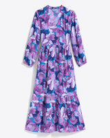 The Draper James Katie Midi Dress boasts a crewneck with a center front keyhole, vibrant floral fabric featuring purple, pink, and white flowers on blue, long sleeves, and a ruffled hem for elegance.