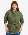 A person wears the Draper James Field Jacket in Green Twill, featuring a belted waist and buttoned chest pocketsâ€”an ideal pick for fall style against a plain background.