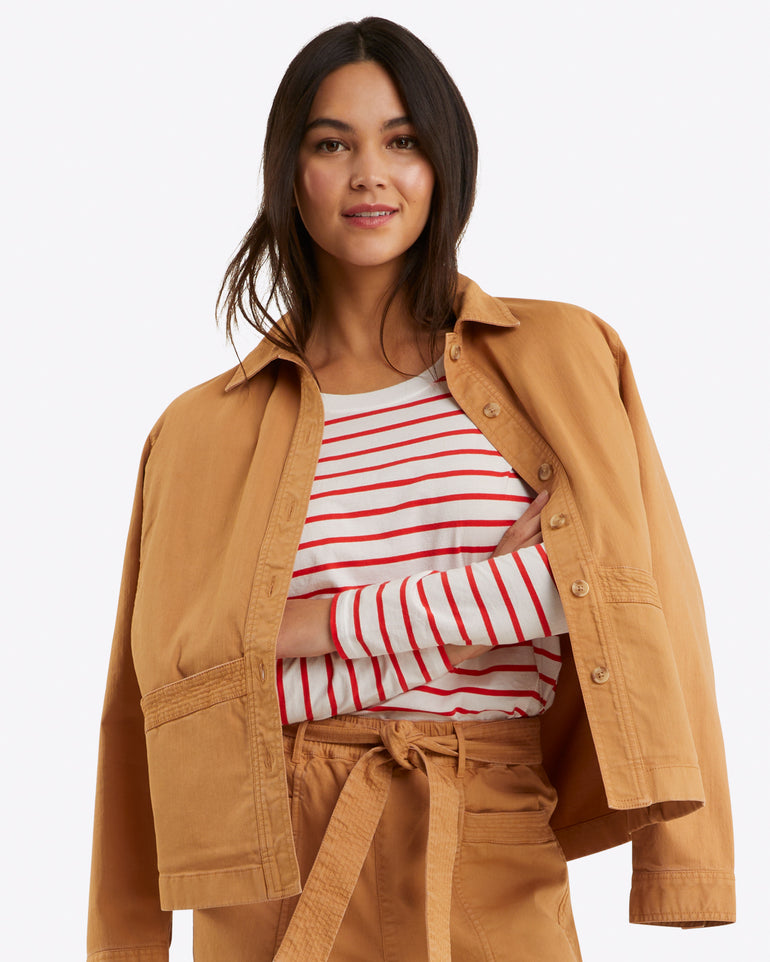 A person in a Draper James Utility Jacket in Cotton Twill over a red and white striped shirt, paired with matching tan pants, stands against a plain background.