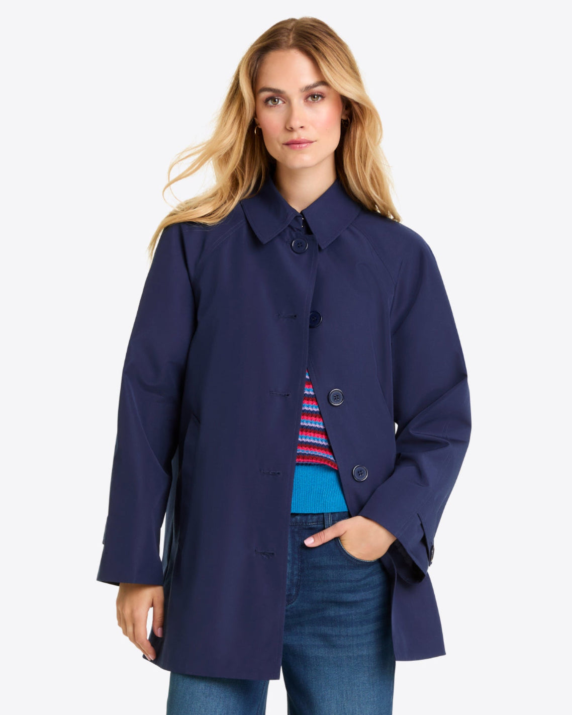 A person wearing a Draper James Button Front Coat in navy blue over a colorful sweater and blue jeans stands against a plain light background.