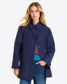 A person wearing a Draper James Button Front Coat in navy blue over a colorful sweater and blue jeans stands against a plain light background.