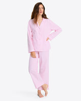 Someone in the Linda Pajama Set, showcasing pink and white striped pants with an elastic waist, is barefoot against a plain backdrop.