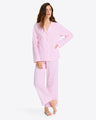 Someone in the Linda Pajama Set, showcasing pink and white striped pants with an elastic waist, is barefoot against a plain backdrop.