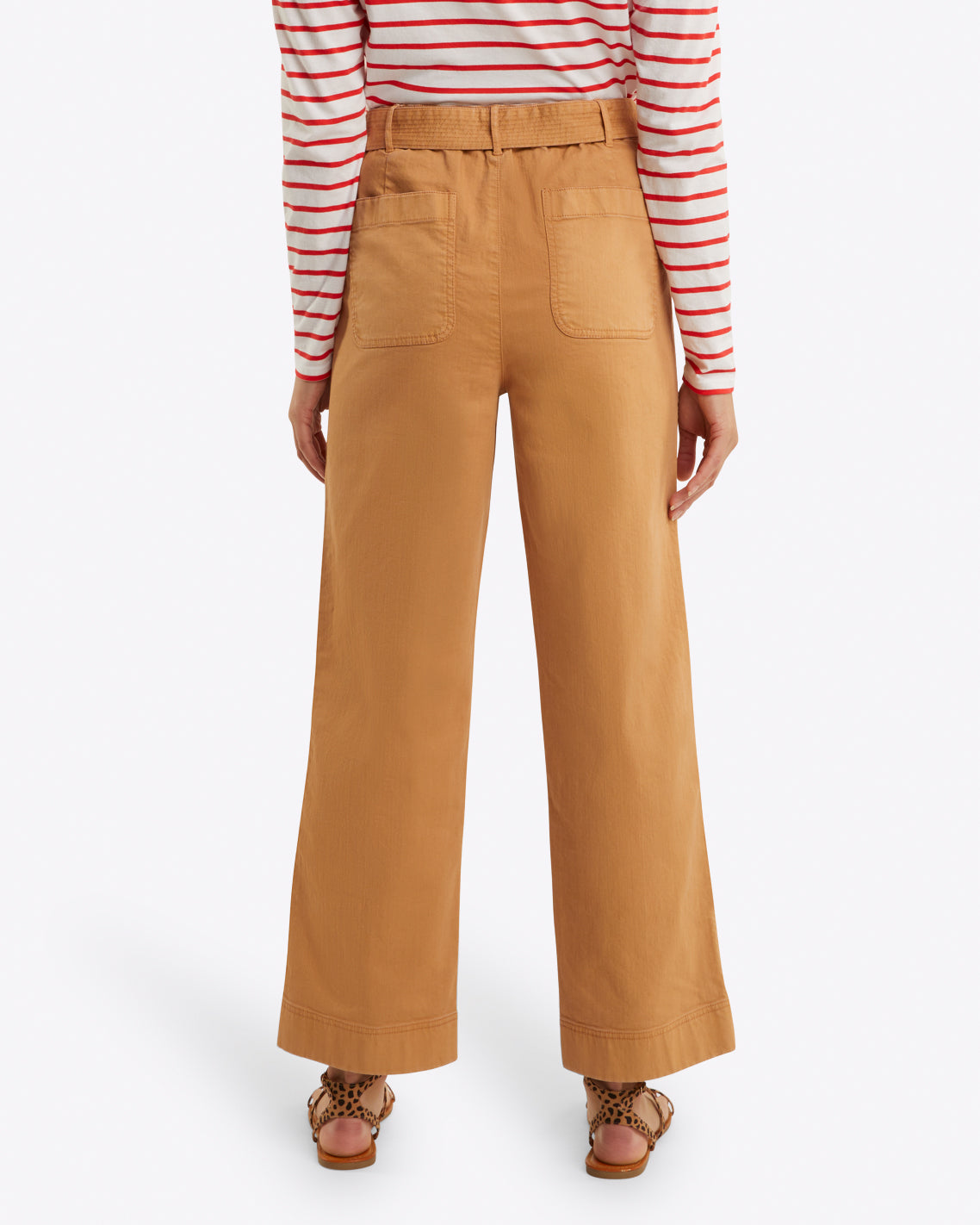 Seen from behind, the person wears a red and white striped top with Draper James' Utility Pant in Cotton Twill, which are high-waisted and tan. The relaxed fit of the stretch-cotton trousers complements their look, finished off with brown sandals.