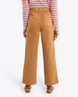 Seen from behind, the person wears a red and white striped top with Draper James' Utility Pant in Cotton Twill, which are high-waisted and tan. The relaxed fit of the stretch-cotton trousers complements their look, finished off with brown sandals.