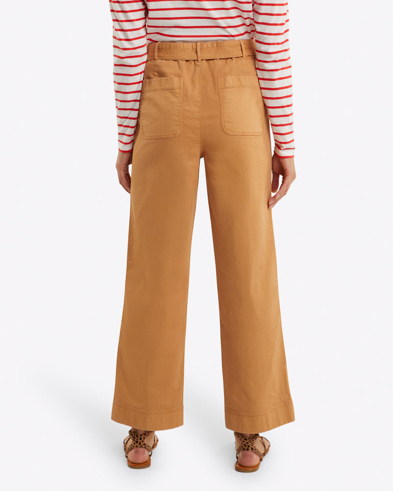 Seen from behind, the person wears a red and white striped top with Draper James' Utility Pant in Cotton Twill, which are high-waisted and tan. The relaxed fit of the stretch-cotton trousers complements their look, finished off with brown sandals.