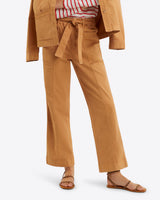 The person in a brown Utility Pant in Cotton Twill by Draper James and matching jacket looks effortlessly stylish. Tied at the waist over a red and white striped shirt, the outfit is completed with brown sandals for a chic yet comfortable look.
