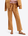 The person in a brown Utility Pant in Cotton Twill by Draper James and matching jacket looks effortlessly stylish. Tied at the waist over a red and white striped shirt, the outfit is completed with brown sandals for a chic yet comfortable look.