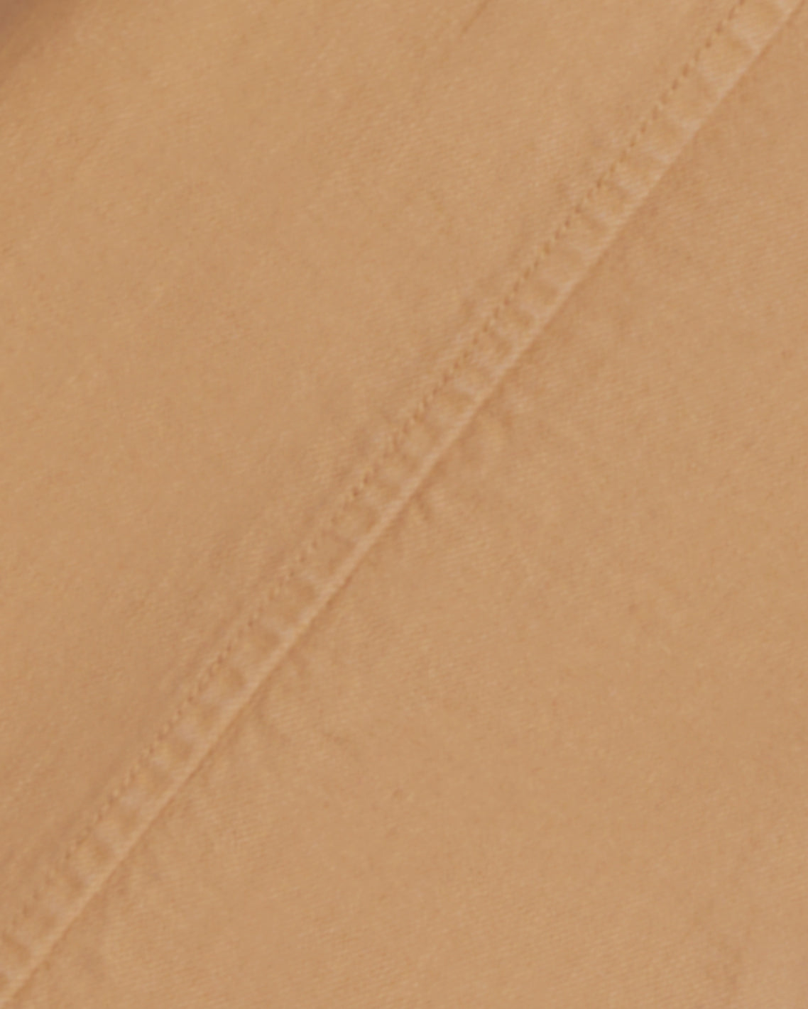 Close-up of beige stretch-cotton fabric with a diagonal seam, great for crafting Draper James' relaxed-fit Utility Pant in Cotton Twill.