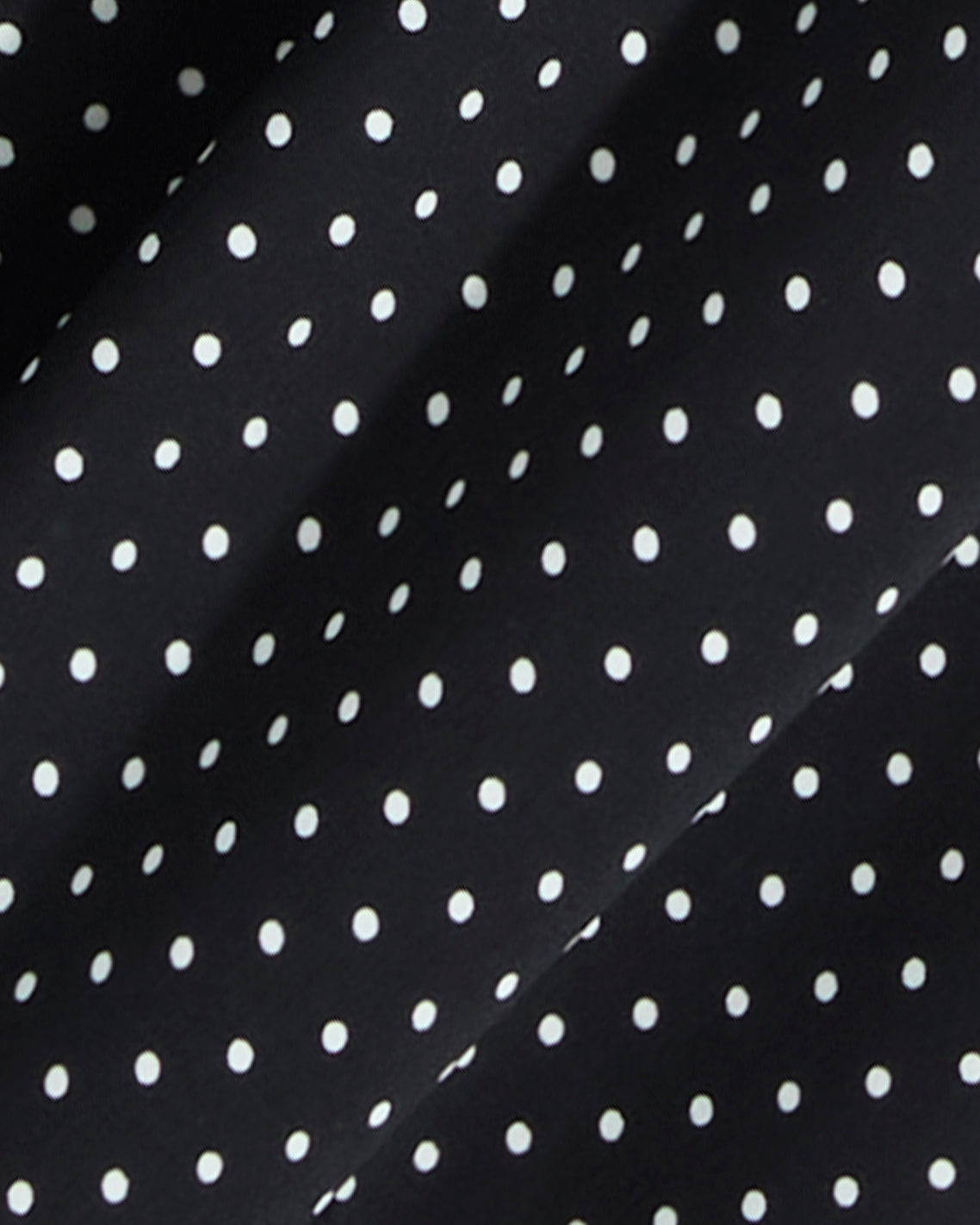 Close-up of the Draper James Midi Skirt in Polka Dot, featuring black fabric with evenly spaced white dots and subtle folds—ideal for a smocked waist or a flowing silhouette.