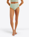 A person models the Draper James Smocked Bikini Bottom with a matching striped crop top, styled as a seersucker swimsuit, while standing barefoot against a plain white background.