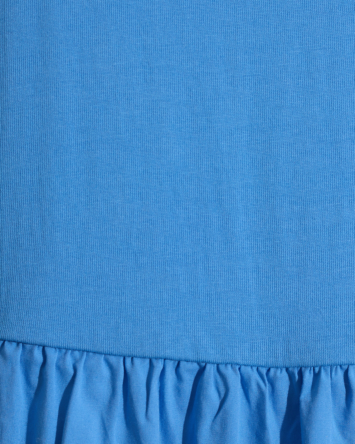 Close-up of the Draper James Lila Mixed Media Midi Dress in Light Blue, showcasing a ribbed cotton bodice and a gathered, ruffled skirt.