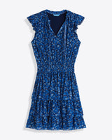The Draper James Alana Tiered Dress in Blue Scattered Ditsy features a v-neck, ruffled cap sleeves, cinched waist, and tiered skirt, shown on a white background.