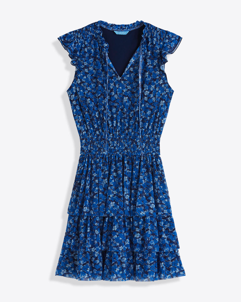 The Draper James Alana Tiered Dress in Blue Scattered Ditsy features a v-neck, ruffled cap sleeves, cinched waist, and tiered skirt, shown on a white background.