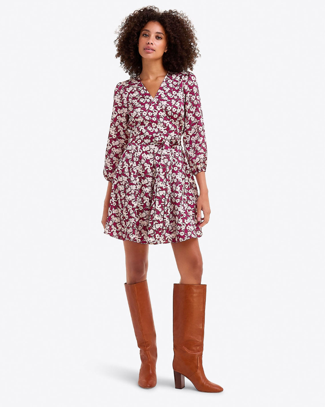 A woman wears the Draper James Jordan Long-Sleeve Wrap Dress in hammered satin with brown knee-high boots, standing against a plain white background.