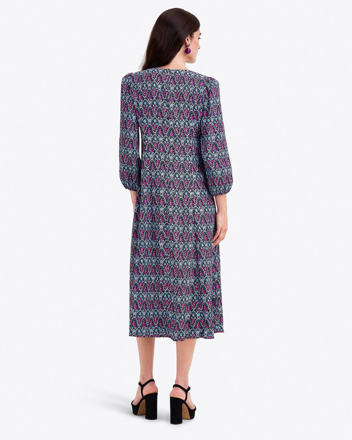 A woman faces away, wearing the Draper James Long-Sleeve Midi Dress in multicolored geometric crinkle chiffon and black platform sandals.