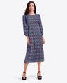A woman wears the Draper James Long-Sleeve Midi Dress in blue and pink crinkle chiffon, featuring a crewneck and patterned design, standing with one hand by her side and the other near her hip, styled with black platform heels.