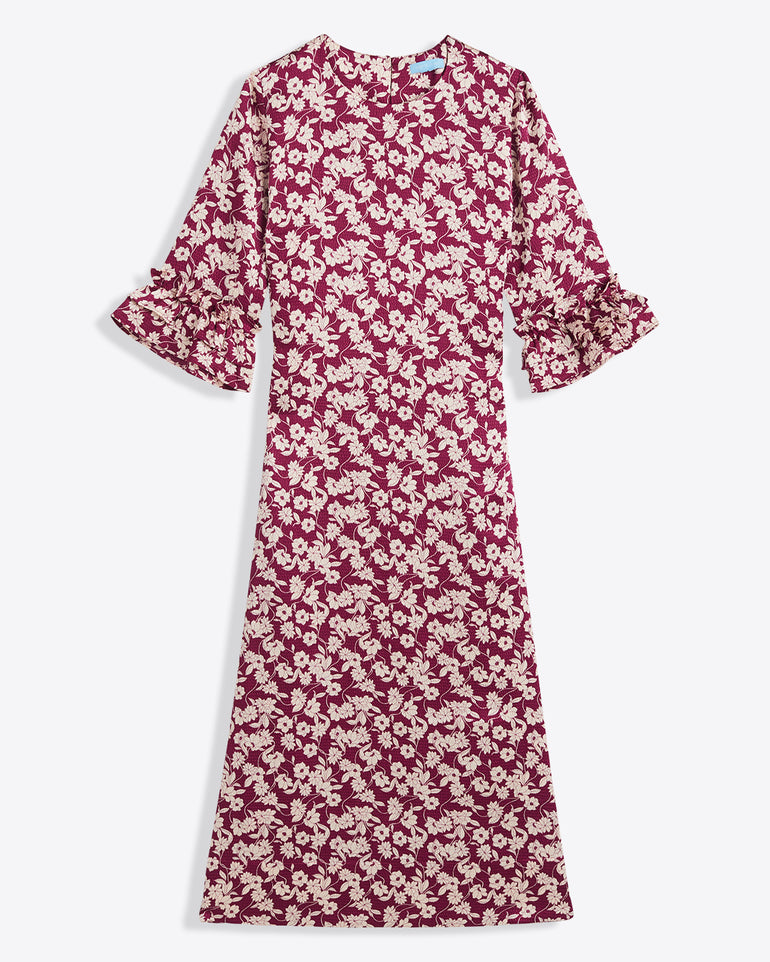 The Draper James Crewneck Midi Dress in hammered satin features a maroon and white floral pattern, ruffled cuffs, and a round neckline. Ankle-length with long sleeves. Machine wash cold for easy care.