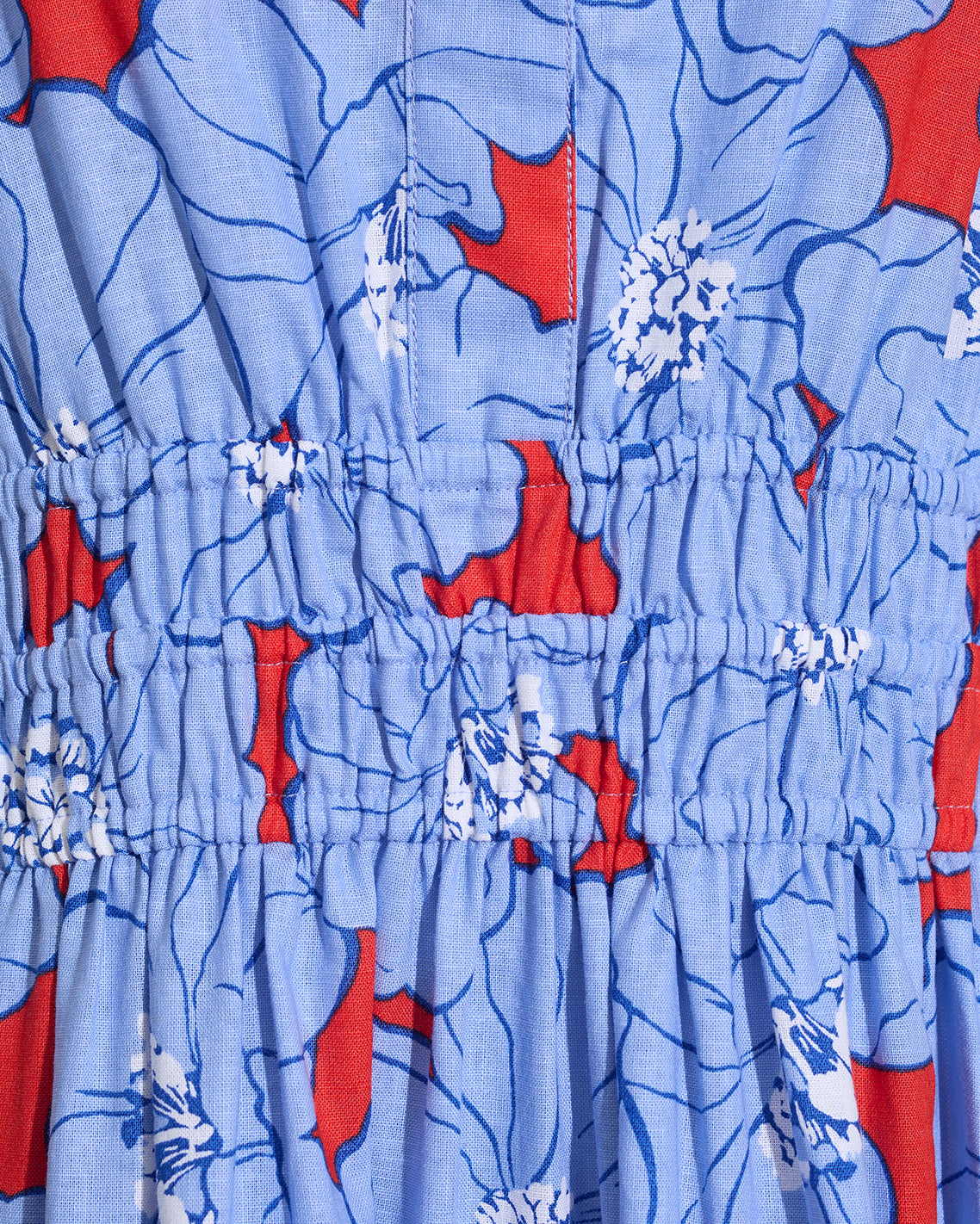 Close-up of the Draper James Hollie Midi Dress in Floating Floral, featuring blue cotton-linen fabric with red and white florals and gathered elasticized stitching.