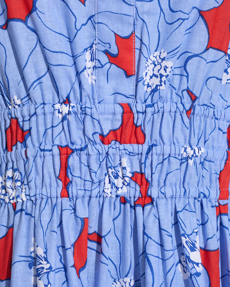 Close-up of the Draper James Hollie Midi Dress in Floating Floral, featuring blue cotton-linen fabric with red and white florals and gathered elasticized stitching.