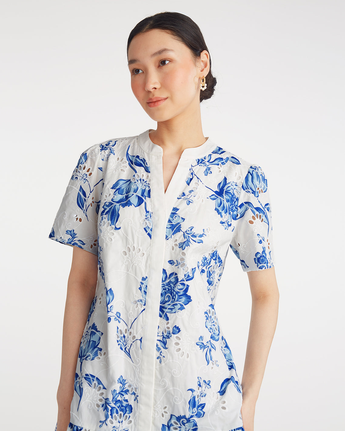 A woman wears the Draper James Molly Mini Dress in Magnolia Toile—100% cotton with blue floral print, short sleeves, and a v-neck—posing against a plain white background.
