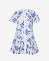 The Draper James Molly Mini Dress in Magnolia Toile is a white, short-sleeve 100% cotton dress with a blue floral print, fitted bodice, V-neckline, and flared ruffled hem.