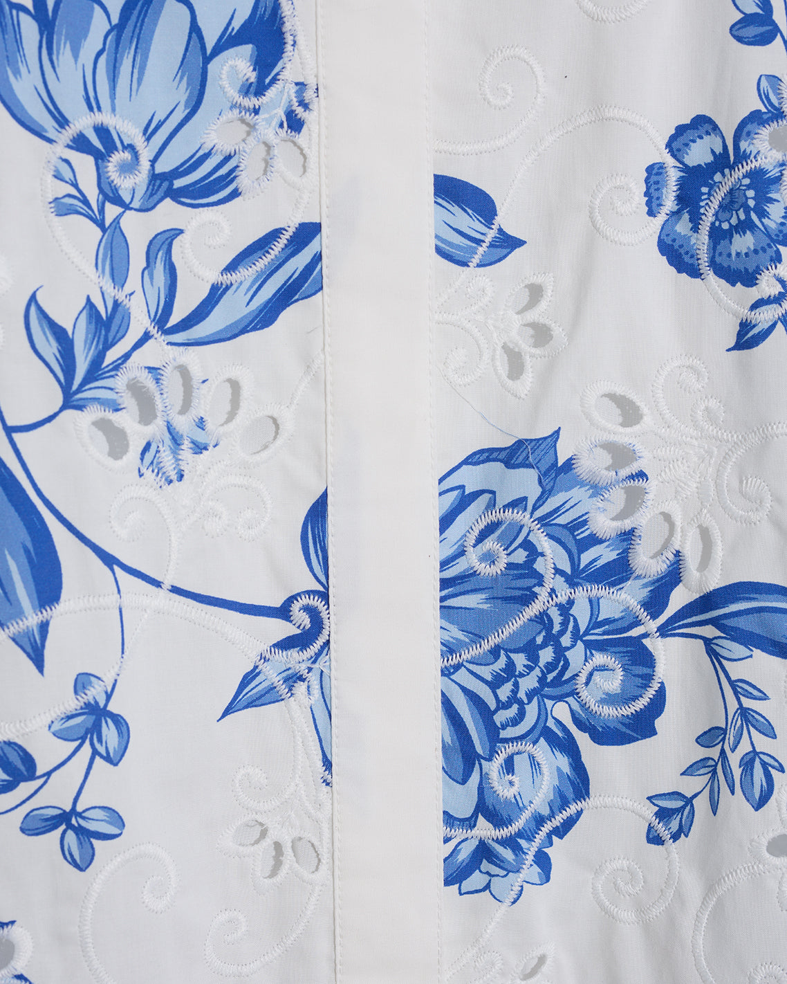 Close-up of the Draper James Molly Mini Dress in Magnolia Toile, featuring 100% cotton white fabric with blue floral embroidery and a vertical seam down the center.