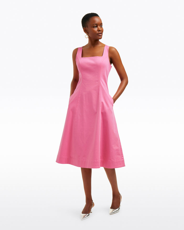 A person wears the Draper James Genevieve Square Neck Sleeveless Midi Dress in pink with silver heels, standing against a plain white background.