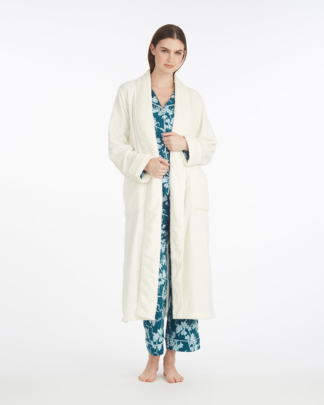 A woman stands barefoot in the Draper James Shawl Collar Robe over blue floral pajamas, set against a plain white background.
