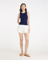 A woman stands against a plain white background wearing the Draper James Sweater Tank in navy with white trim, paired with white shorts and tan woven slide sandals.