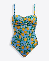 The Draper James Lemon Blossom Bandeau One Piece is a lemon print swimsuit with thin straps, a blue background, green leaves, and UPF 50+ protection—perfect for sunny days.