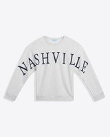 The Draper James Nashville Crewneck Sweatshirt features long sleeves, a light gray color, and bold black "NASHVILLE" lettering—perfect for country music fans.