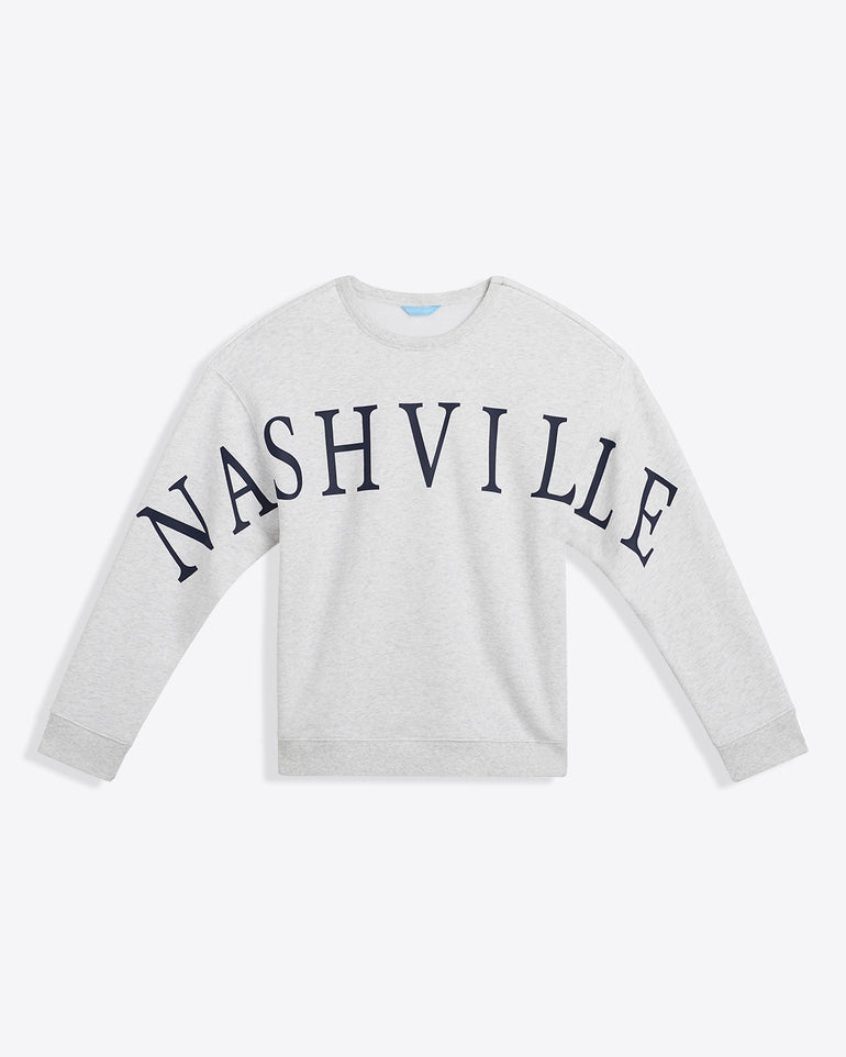The Draper James Nashville Crewneck Sweatshirt features long sleeves, a light gray color, and bold black "NASHVILLE" lettering—perfect for country music fans.