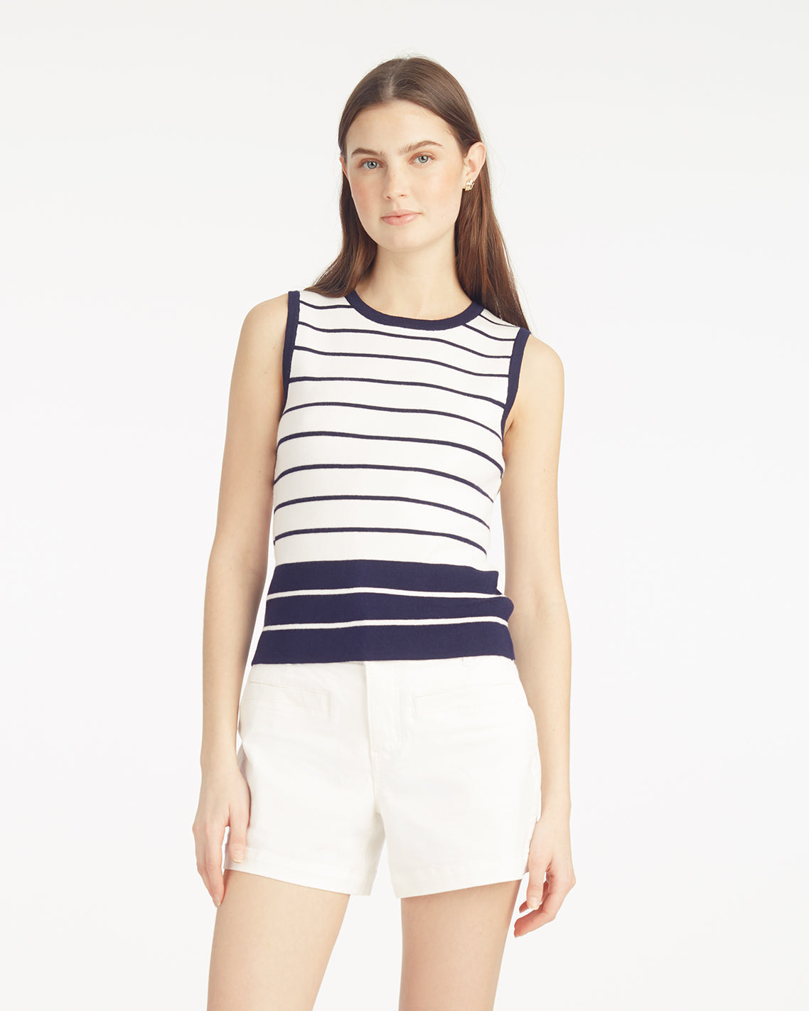 A woman faces forward against a white background, wearing the Draper James Sweater Tankâ€”a stylish striped polyester-blend topâ€”paired with white shorts.