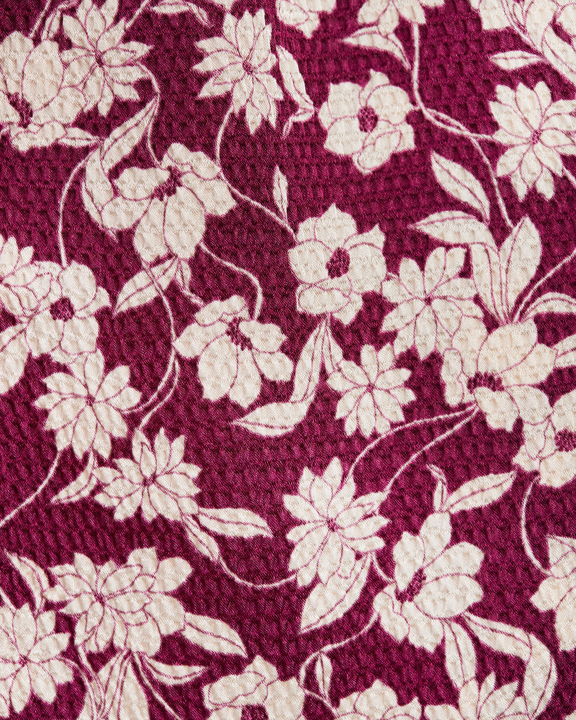The Jordan Long-Sleeve Wrap Dress in Hammered Satin by Draper James features a maroon background with an off-white floral pattern of large flowers and leaves, offering a refined, textured look perfect for elegant occasions.