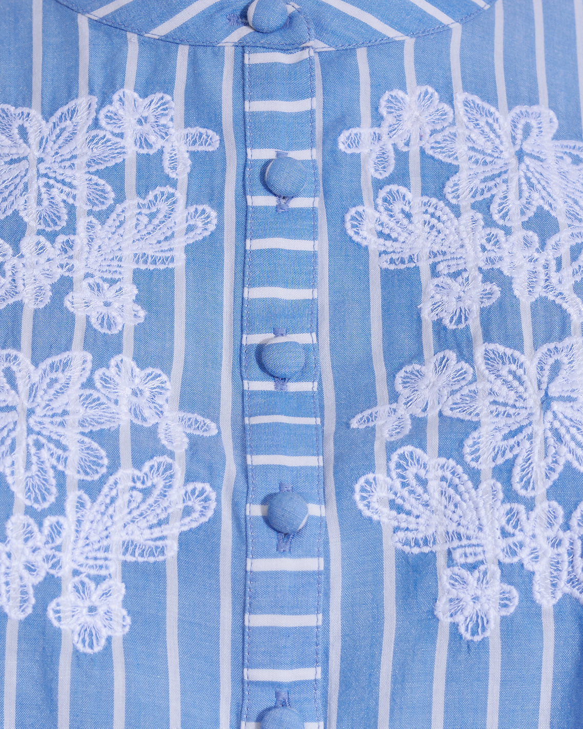 Close-up of the Puff Sleeve Top with Floral Embroidery by Draper James, showcasing blue and white stripes, delicate white floral embroidery, and fabric-covered buttonsâ€”a perfect summer top.