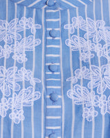 Close-up of the Puff Sleeve Top with Floral Embroidery by Draper James, showcasing blue and white stripes, delicate white floral embroidery, and fabric-covered buttonsâ€”a perfect summer top.