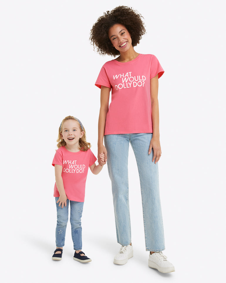 An adult and a child hold hands against a white background, sporting matching Draper James Kids WWDD Pink T-Shirts with "WHAT WOULD DOLLY DO?" on jersey cotton.
