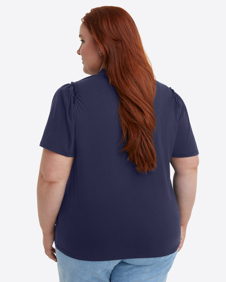 A person with long red hair, wearing the Draper James Short Sleeve Easy Knit Top in Navy and light blue jeans, is shown from the back.